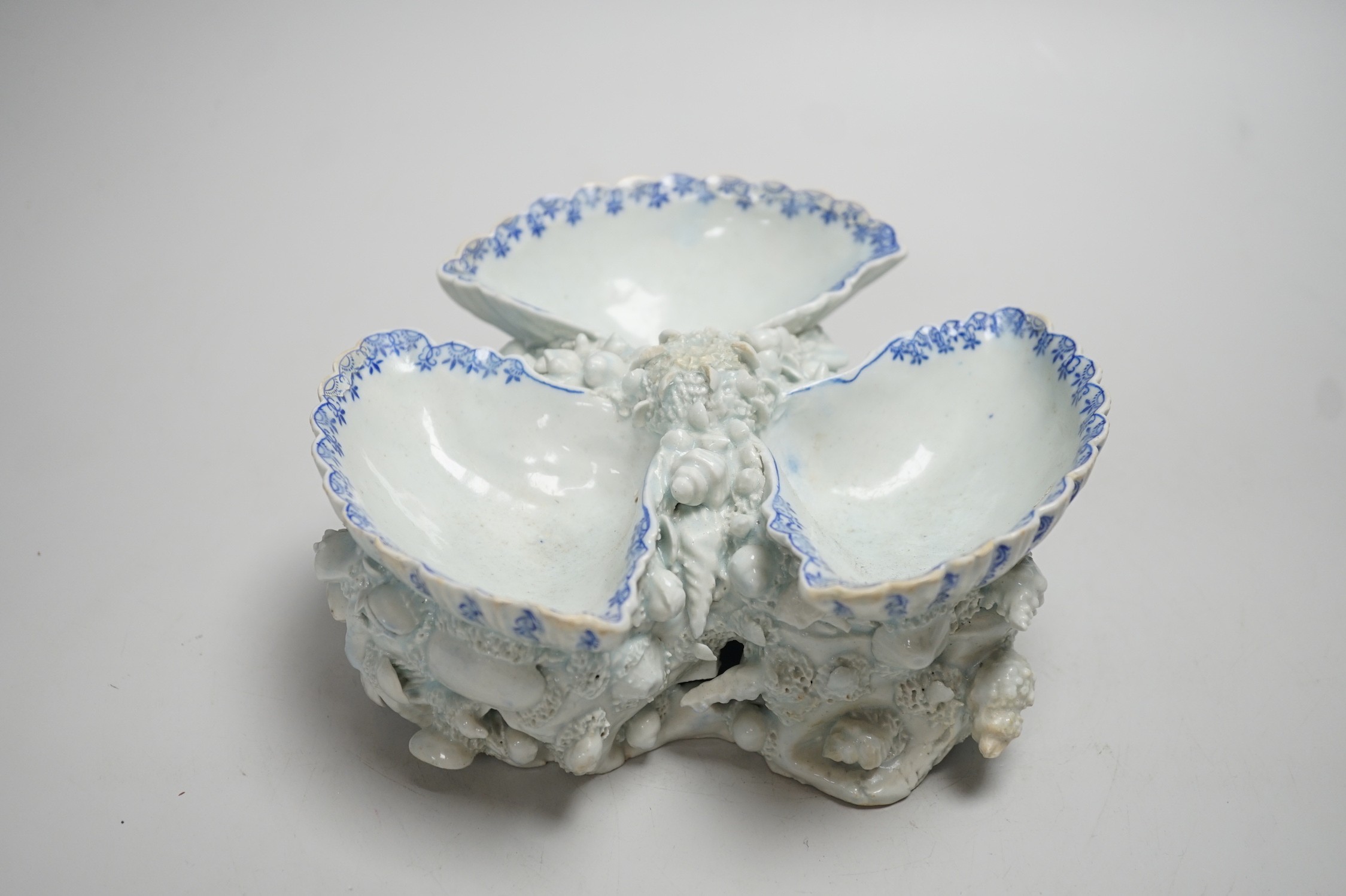 An early Bow porcelain three shell salt, the naturalistically modelled shells picked out in underglaze blue, on a shell and coral encrusted base, 8cm high